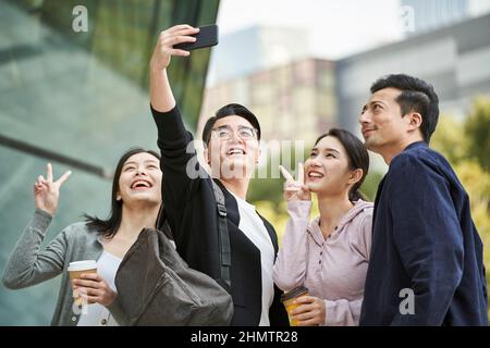 Eine Gruppe junger asiatischer Menschen, die auf der Straße ein Selfie mit dem Handy machen, glücklich und lächelnd Stockfoto