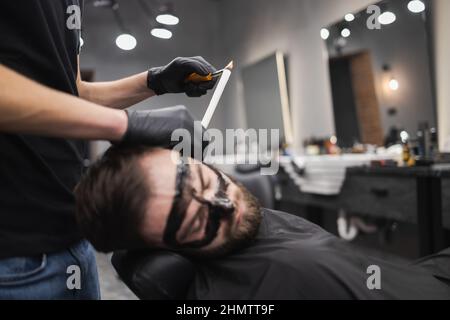 Der Mann in einem Schönheitssalon entfernt Ohrenwachs mit Kerzen. Männlich genießt eine Spa-Behandlung Stockfoto