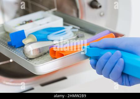 Junger Zahnarzt platziert medizinischen Autoklav zur Sterilisation chirurgischer und anderer Instrumente Stockfoto