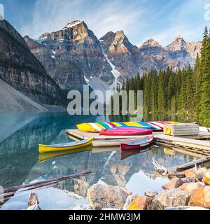 Am Moraine Lake im Banff National Park, Alberta, Kanada, könnt ihr Kanus fahren und die schneebedeckten Gipfel der kanadischen Rocky Mountains im Hintergrund bewundern Stockfoto