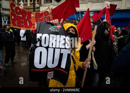 Manchester, Großbritannien. 12th. Februar 2022. Demonstranten marschieren mit Plakaten durch die Stadt. Hunderte von Menschen gehen auf die Straße, um gegen die steigenden Lebenshaltungskosten zu protestieren. Unter dem Motto „We Can't Pay for This Crisis“, organisiert von der Volksversammlung, werden landesweit Demonstrationen gegen die Torys und ihre Handhabung der aktuellen und sich immer weiter verschlechternden Situation, in der sich Tausende befinden, abgehalten. Kredit: Andy Barton/Alamy Live Nachrichten Stockfoto