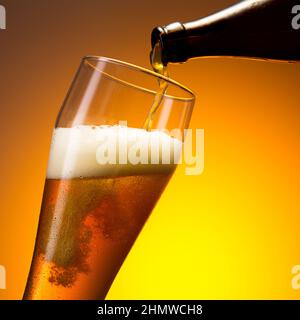 Weizenbier fließt in ein Glas Stockfoto