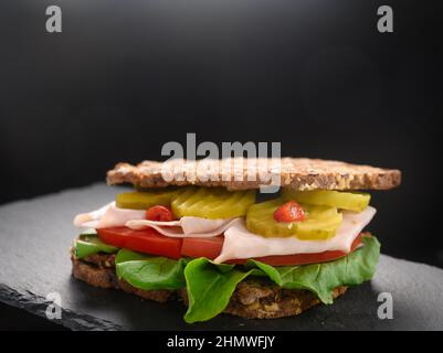 Ein schneller Snack in Form eines Sandwiches. Der Hintergrund ist schwarz, auf dem Sie Ihren Text einfügen können. Sandwich - gesunde Lebensmittel aus Brot und Gemüse Stockfoto