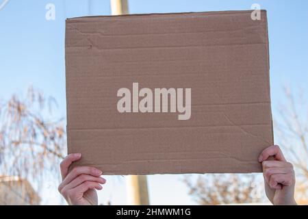 Frau mit leerem Karton und protestiert gegen etwas. Platz für Text auf Karton kopieren. Stockfoto