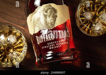 Ternopil, Ukraine - 29. April 2021: Eine Flasche Buffalo Trace Kentucky Straight Bourbon Whiskey und zwei Gläser mit Eis und Bourbon auf einem Holztisch Stockfoto