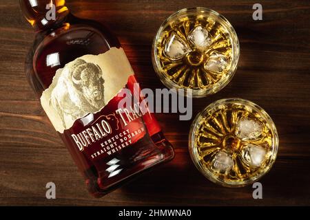 Ternopil, Ukraine - 29. April 2021: Eine Flasche Buffalo Trace Kentucky Straight Bourbon Whiskey und zwei Gläser mit Eis und Bourbon auf einem Holztisch Stockfoto