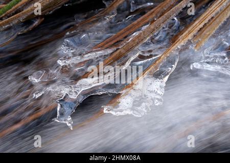 Eiszapfen hängen in der Nähe über dem Wasserstrom Stockfoto