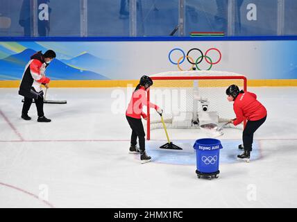 (220212) -- PEKING, 12. Februar 2022 (Xinhua) -- Mitarbeiter reinigen die Eisbahn während der Pause eines Eishockeyspiels im Wukesong Sports Center in Peking, der Hauptstadt Chinas, am 8. Februar 2022 mit verschiedenen Werkzeugen. Als die chinesischen Eishockeyspieler bei den Olympischen Winterspielen 2022 in Peking auftauchten, zieht dieses Spiel immer mehr die Aufmerksamkeit der Öffentlichkeit auf sich. Im Wukesong Sports Center in Peking stellten Mitarbeiter der Eishockey-Veranstaltungen die Eiswürfel in Kühlboxen. Der Puck aus vulkanisiertem Gummi ist eine flache Festplatte, die vor dem Spiel eingefroren werden muss, um die Elastizität während des Spiels zu verringern Stockfoto