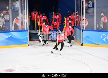 (220212) -- PEKING, 12. Februar 2022 (Xinhua) -- Mitarbeiter tragen ihre Werkzeuge, um die Eisbahn während der Pause eines Eishockeyspiels im Wukesong Sports Center in Peking, der Hauptstadt von China, zu reinigen, 11. Februar 2022. Als die chinesischen Eishockeyspieler bei den Olympischen Winterspielen 2022 in Peking auftauchten, zieht dieses Spiel immer mehr die Aufmerksamkeit der Öffentlichkeit auf sich. Im Wukesong Sports Center in Peking stellten Mitarbeiter der Eishockey-Veranstaltungen die Eiswürfel in Kühlboxen. Der Puck aus vulkanisiertem Kautschuk ist eine flache Festplatte, die vor dem Spiel eingefroren werden muss, um die Elastizität während zu verringern Stockfoto