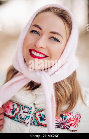 Schöne russische Frau im Kopftuch, Portrait. Eine liebenswerte Frau lächelt und schaut im Winter auf die Kamera. Stockfoto