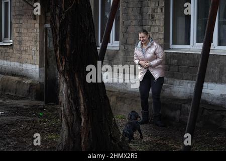 Gornyak, Ukraine. 9th. Februar 2022. Eugenia Mazur, 26, mit ihrem Hund vor ihrer Wohnung am 9. Februar 2022. Igor und Eugenia Mazur, die Eltern von 5 Kindern, die alle unter 8 Jahre alt sind, leben etwa 10 Meilen von der Donezker Front in Gornyak, Ukraine. Die Familie kämpft darum, genügend Arbeit für Lebensmittel und Rechnungen zu finden und bleibt besorgt, während die russischen Streitkräfte an der ukrainischen Grenze mobilisieren. (Bild: © Michaal Nigro/Pacific Press via ZUMA Press Wire) Stockfoto