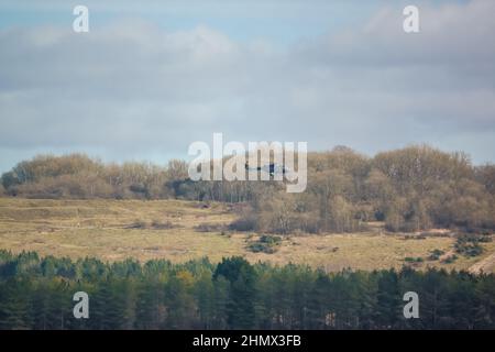 Britische Armee AgustaWestland AW159 Wildcat AH1 Hubschrauber fliegen tief über die offene Landschaft Stockfoto