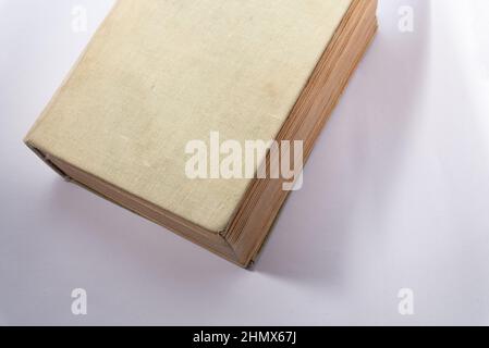 Altes Buch mit vergilbten Seiten und einem Stoffeinband. Dickes Buch isoliert auf weißem Hintergrund. Stockfoto