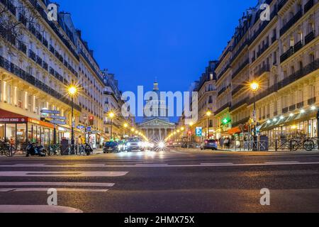 Paris, Frankreich - 11. Februar 2022 : geschäftiges Treiben auf einem Boulevard in Paris und das berühmte Pantheon-Denkmal im Hintergrund bei Nacht Stockfoto