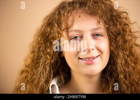 Nahaufnahme Foto von einer schönen schönen attraktiven jungen Frau Rotschopf suchen ruhig und glänzend über einem goldenen Hintergrund. Stockfoto