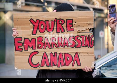 Halifax, Nova Scotia, Kanada. 12th. Februar 2022. Kontern Sie Demonstranten mit dem Schild „You're Peinlich Canada“ auf dem Weg des Konvois und der anschließenden Kundgebung, um ihre Ablehnung zu zeigen und zu zeigen, wie die Teilnehmer das Gefühl haben, das Land in Verlegenheit zu bringen. Menschen aus der ganzen Provinz fuhren gegen alle Covid-19-Mandate nach Halifax am zweiten Wochenende des Freedom Convoy 2022. Stockfoto