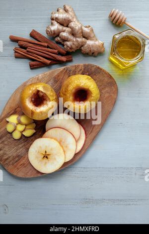 Gebackener Apfel mit Honig, Zimt und Ingwer auf einem hellen Holztisch Stockfoto