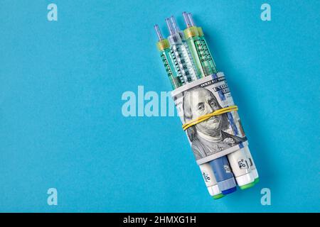 Insulin-Spritzenstifte in Dollarscheine auf blauem Hintergrund verpackt Stockfoto