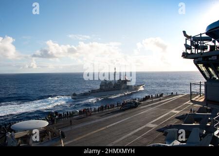 220209-N-PQ495-1284 PAZIFISCHER OZEAN (FEB 9, 2022) Matrosen beobachten, wie der Lenkraketen-Kreuzer USS Lake Champlain (CG 57) der Ticonderoga-Klasse neben dem Flugzeugträger USS Carl Vinson (CVN 70) der Nimitz-Klasse umherfliegt, 9. Februar 2022. Vinson führt derzeit routinemäßige Seeoperationen in der US-Flotte von 3rd durch. (USA Navy Foto von Mass Communication Specialist Seaman Larissa T. Dougherty) Stockfoto