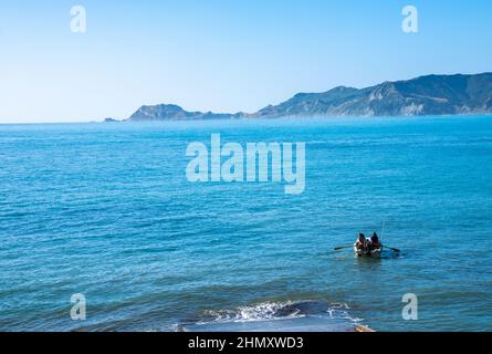 Tokomaru Bay Neuseeland - 5 20222. Februar; zwei Fischer fahren im Beiboot von der Bootsrampe in der Bucht aus. Stockfoto