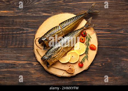 Tafel mit leckeren geräucherten Makrelenfischen auf dunklem Holzhintergrund Stockfoto