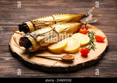 Tafel mit leckeren geräucherten Makrelenfischen auf dunklem Holzhintergrund Stockfoto