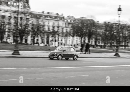 Schwarz-Weiß-Foto eines klassischen italienischen Autos, typischer Fiat 500 auf der Straße Stockfoto