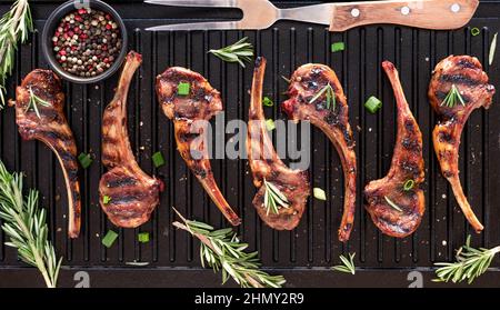 Gegrillte Lammkoteletts auf einer Grillpfanne mit Rosmarin und Pfefferkörnern. Stockfoto