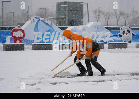 Peking, China. 12th. Februar 2022. Arbeiter schaufeln Neuschnee, der sich über Nacht vor dem Hauptmedienzentrum bei den Olympischen Winterspielen 2022 in Peking am Sonntag, dem 13. Februar 2022 angesammelt hat. Foto von Paul Hanna/UPI Credit: UPI/Alamy Live News Stockfoto