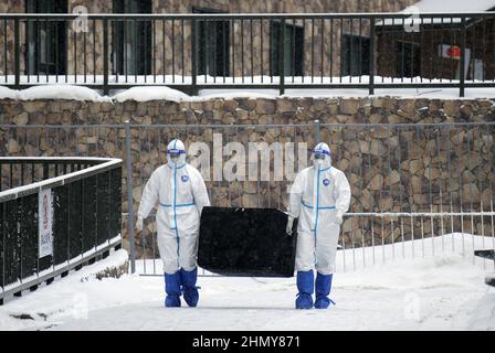 Zhangjiakou, China. 12th. Februar 2022. Arbeiter, die in Hazmat-Anzügen gekleidet sind, tragen am Sonntag, den 13. Februar 2022, bei den Olympischen Winterspielen 2022 in Zhangjiakou, China, einen Container in einem Hotel in der schützenden COVID-Blase. Foto von Bob Strong/UPI . Kredit: UPI/Alamy Live Nachrichten Stockfoto