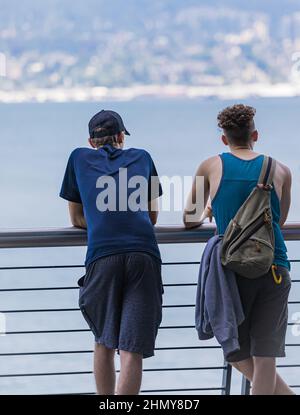 Zwei junge Männer stehen am Pier und genießen den Blick auf das Wasser. Stockfoto