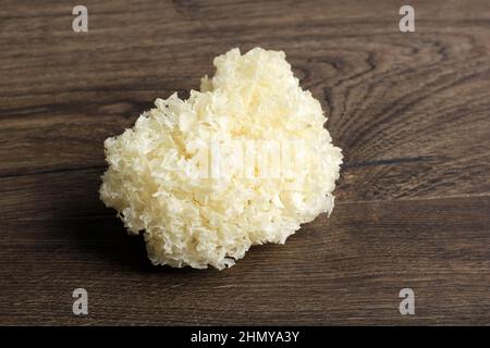 Frischer weißer Pilz (Tremella fuciformis) auf braunem Holztisch, isoliert Stockfoto