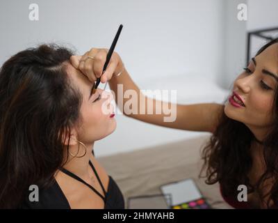 Eine junge Frau macht Make-up Augenbrauenstift zu ihrer Freundin zu Hause an halloween Stockfoto