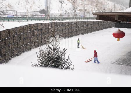 Zhangjiakou, Chinas Provinz Hebei. 13th. Februar 2022. Mitarbeiter reinigen Schnee vor dem Zhangjiakou Mountain Press Center in Zhangjiakou, nordchinesische Provinz Hebei, 13. Februar 2022. Quelle: Peng Ziyang/Xinhua/Alamy Live News Stockfoto