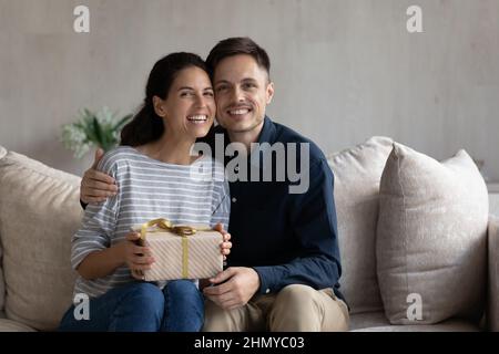 Aufgeregt Frau nimmt Geschenk von glücklichen Ehemann Stockfoto