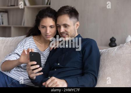 Fokussiertes Millennial-Paar, das Online-Dienste auf dem Smartphone nutzt Stockfoto