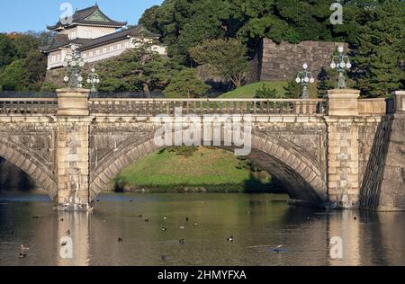 Der Blick auf die SeidenIshibashi-Brücke (ein Spitzname ist Meganebashi oder Brillen) über das Wasser des Nijubashi-Grabens und des Fushimi-Turms von Kyuden aus gesehen Stockfoto