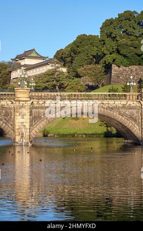 Der Blick auf die SeidenIshibashi-Brücke (ein Spitzname ist Meganebashi oder Brillen) über das Wasser des Nijubashi-Grabens und des Fushimi-Turms von Kyuden aus gesehen Stockfoto