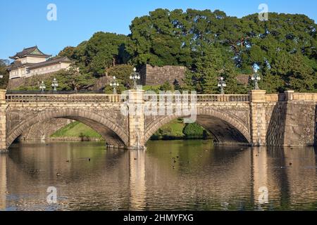 Der Blick auf die SeidenIshibashi-Brücke (ein Spitzname ist Meganebashi oder Brillen) über das Wasser des Nijubashi-Grabens und des Fushimi-Turms von Kyuden aus gesehen Stockfoto