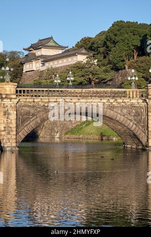 Der Blick auf die SeidenIshibashi-Brücke (ein Spitzname ist Meganebashi oder Brillen) über das Wasser des Nijubashi-Grabens und des Fushimi-Turms von Kyuden aus gesehen Stockfoto