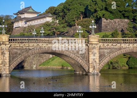 Der Blick auf die SeidenIshibashi-Brücke (ein Spitzname ist Meganebashi oder Brillen) über das Wasser des Nijubashi-Grabens und des Fushimi-Turms von Kyuden aus gesehen Stockfoto