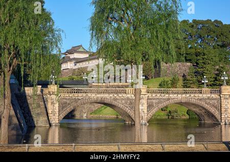 Der Blick auf die SeidenIshibashi-Brücke (ein Spitzname ist Meganebashi oder Brillen) über das Wasser des Nijubashi-Grabens und des Fushimi-Turms von Kyuden aus gesehen Stockfoto