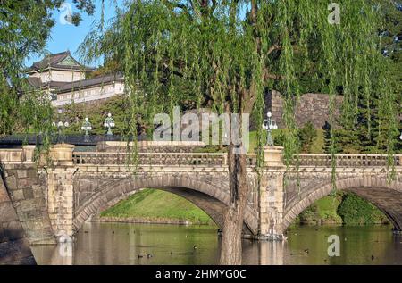 Der Blick auf die SeidenIshibashi-Brücke (ein Spitzname ist Meganebashi oder Brillen) über das Wasser des Nijubashi-Grabens und des Fushimi-Turms von Kyuden aus gesehen Stockfoto