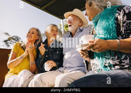 Alte Freunde lachen glücklich beim Tee zusammen. Fröhliche ältere Menschen genießen ihren Sommerurlaub in einem Kurort. Senioren h Stockfoto