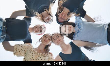 Glückliche Mädchen Freunde umarmt in einem Kreis gegen den blauen Himmel. Stockfoto