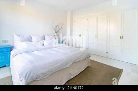 Ein Bild eines komfortablen Bettes neben Einbauschränken in einem Schlafzimmer Stockfoto