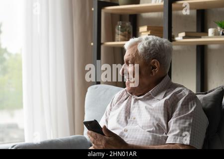 Fröhlicher älterer 80s Mann in Brillen mit Mobiltelefon, Stockfoto