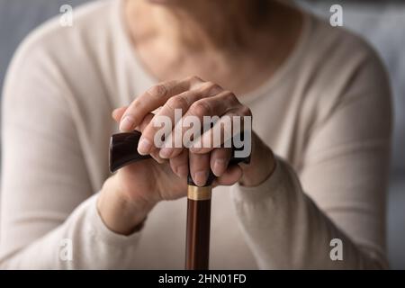 Hände einer älteren Frau, die den Knopf des Gehstockes hält Stockfoto