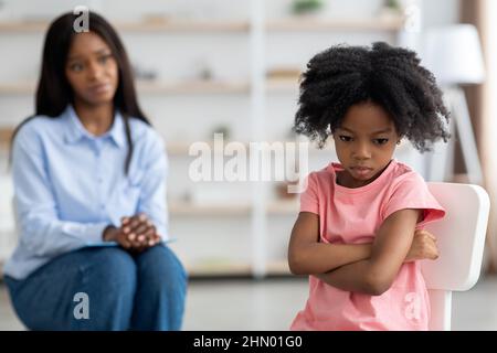 Besorgt schwarze Frau Psychologin Blick auf wütend kleines Mädchen Stockfoto
