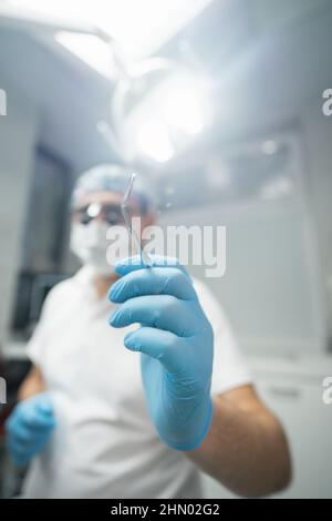 Zahnarzt, der einen Zahnspiegel in der Hand hält Stockfoto